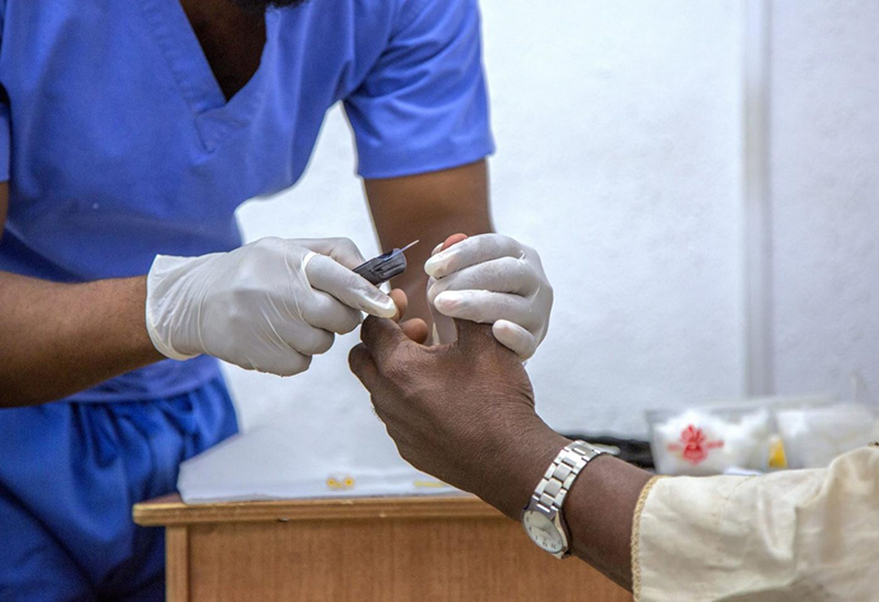 A health worker tests a patient for diabetes.