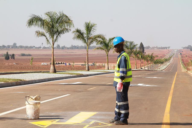 A worker prints lane direction markings on a newly constructed road on the outskirts of Zimbabwe's capital Harare, on July 20, 2024