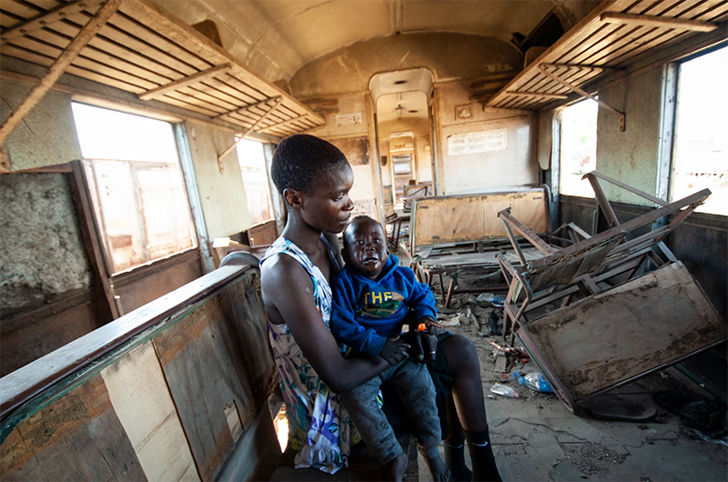 Chipo Makore sits in a passenger rail car at the train station in Harare, Zimbabwe on Aug. 25, where several train cars have been parked over the years as authorities fail to service them.