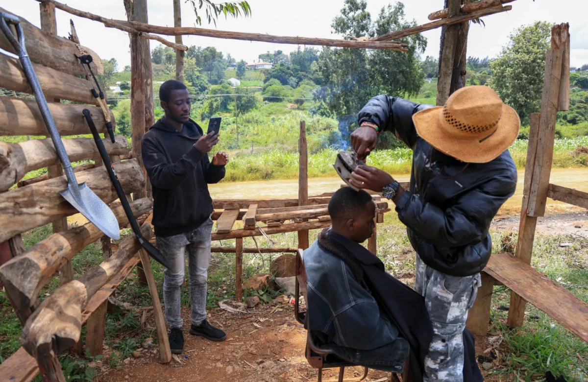 Barber and content creator Safari Martins uses a clothing iron as he shaves Ian Njenga in Kiambu, Kenya